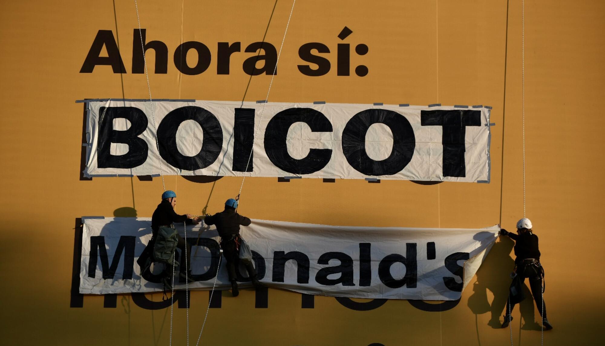 Militantes de Sindicatos de Vivienda y otras organizaciones se descolgaron de un edificio en Madrid para pedir el boicot a McDonald's.