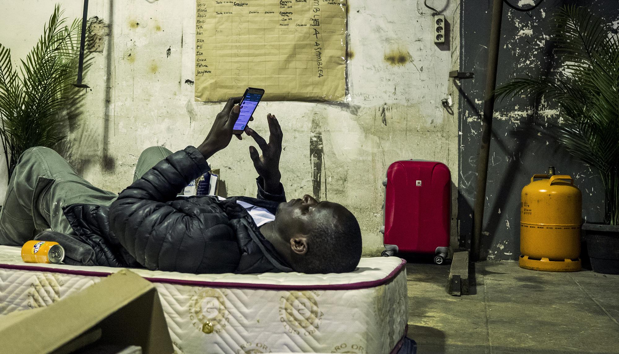 Encierro migrante escuela Massana -joven mirando móvil